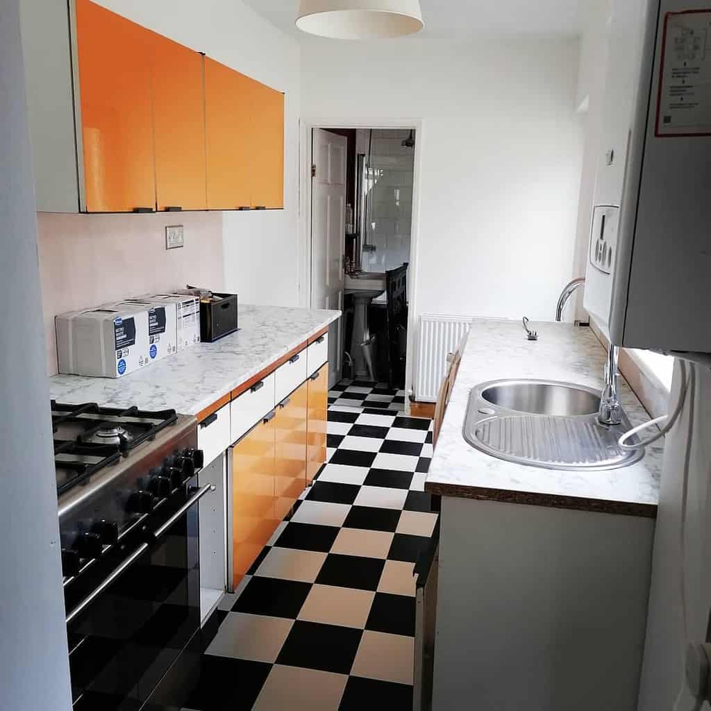 small modern kitchen orange cabinets black and white check tile flooring 