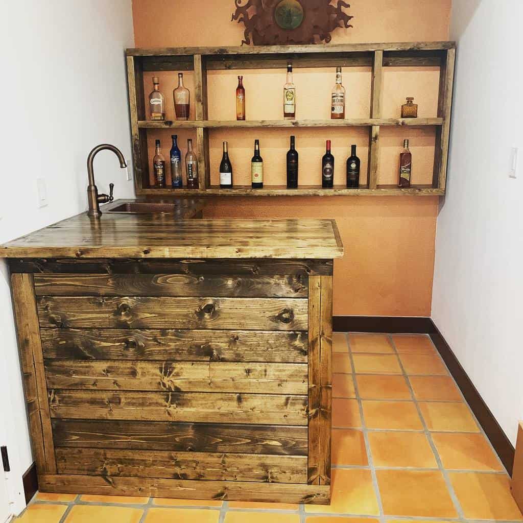 Compact rustic wet bar featuring a natural wood counter and shelves, paired with a terracotta tile floor for a warm and inviting touch.