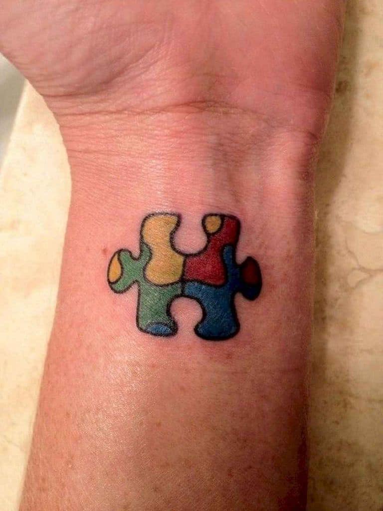 Small full color wrist tattoo of a multi-colored puzzle piece.