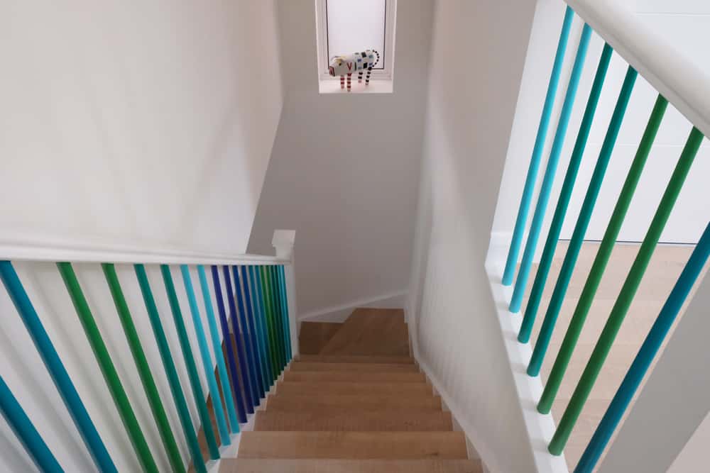 narrow staircase with blue green and purple rails