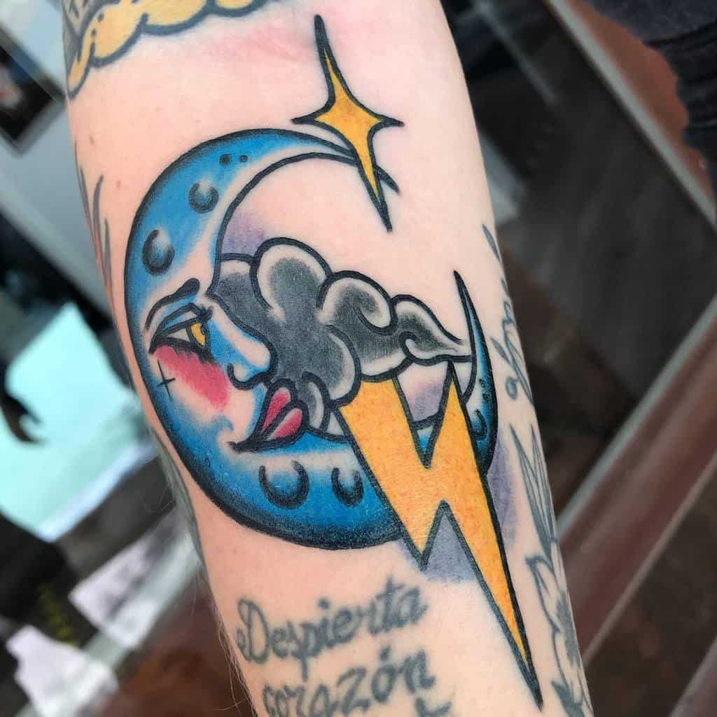 Tattoo of a crescent moon with a face, surrounded by clouds and a lightning bolt, featuring the text "Despierta corazón"