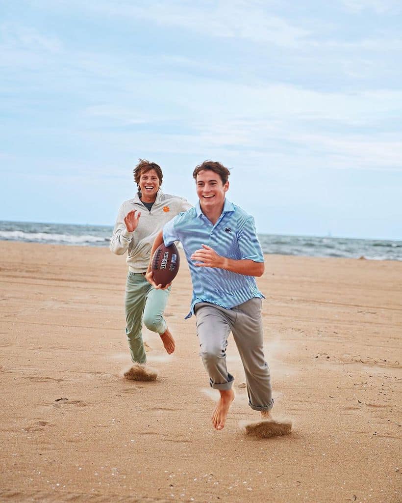 Two Men Playing Football On The Beach And Both Wearing Cuffed Chinos