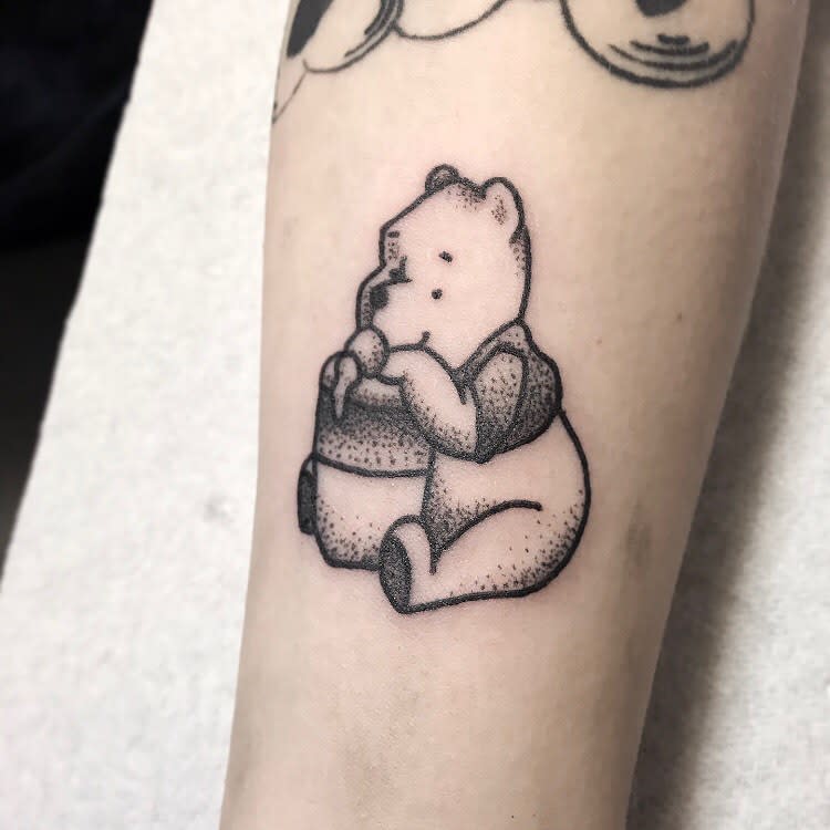 Fine line Pooh bear tattooed on the tricep