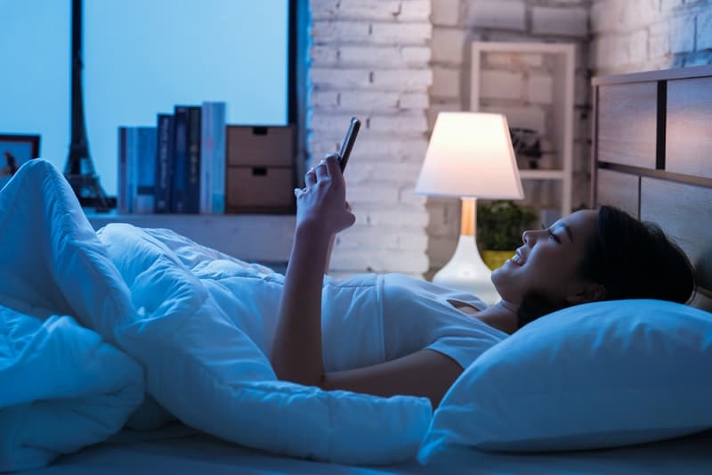 Woman Looking At Phone In Bed