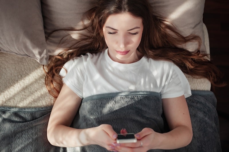 Woman Reading Message Before Going To Sleep