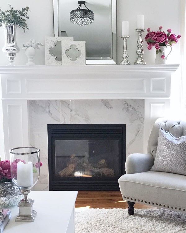 all white marble fireplace surround mantle mirror silver candles sticks gray sofa