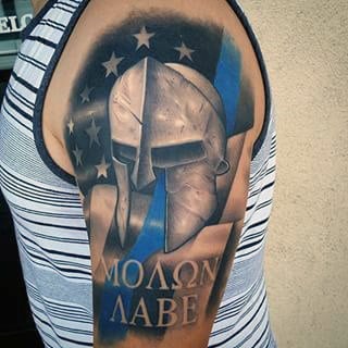 American Flag Stars With Greek Warrior Helmet And Molon Labe Words On Upper Arm Of Gentleman