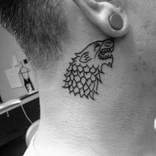 Small neck tattoo featuring black ink outline of angry wolf on man’s neck below ear