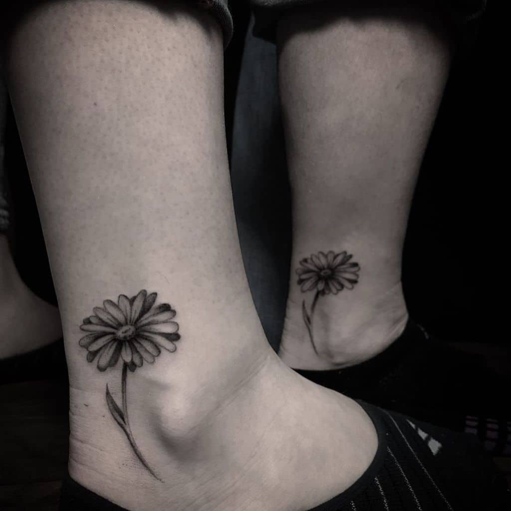 Matching ankle tattoos black and grey fine line daisy