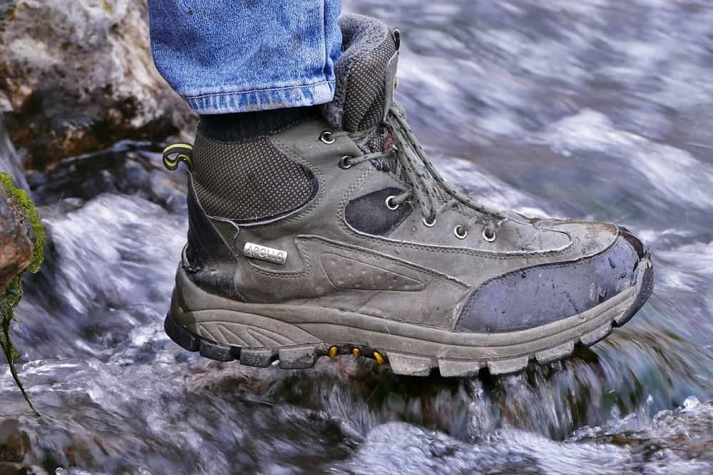 man wearing apollo hiking shoes crossing water outdoor