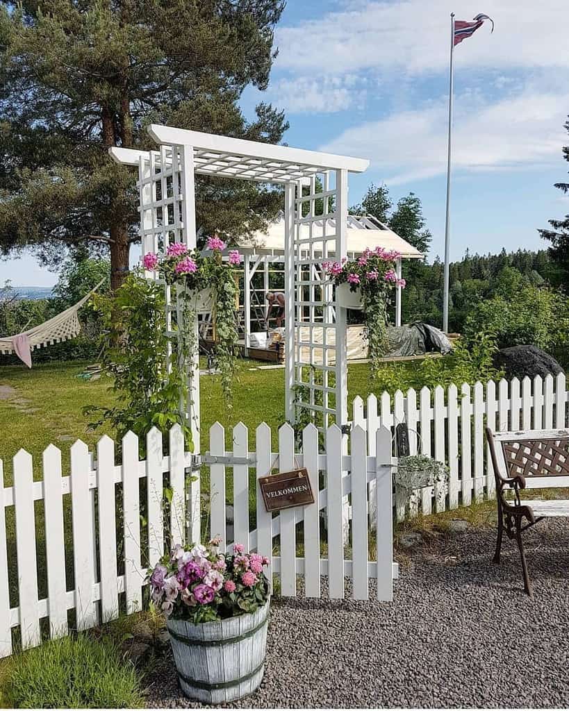 white wood arbor garden trellis with pink flowers white picket fence with gate