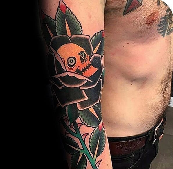 Arm Tattoo Of Black Rose With Thorns And Orange Skull