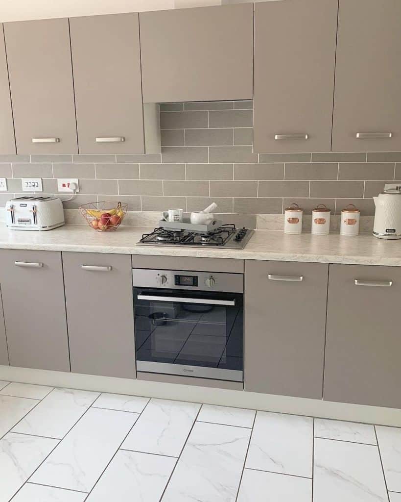 gray cabinet kitchen with gray backsplash tiles and white floor tiles