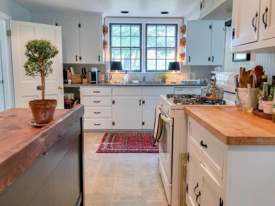 country style kitchen with white cabinets wood countertops white tile backsplash 