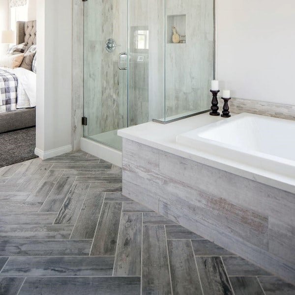 Bathroom with wood-look tile flooring, glass shower, and built-in bathtub with gray accents.