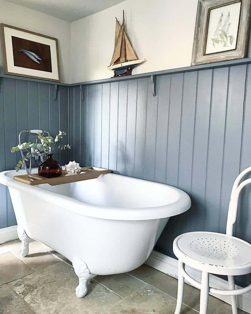 blue bathroom wall paneling white bathtub and vintage chair 