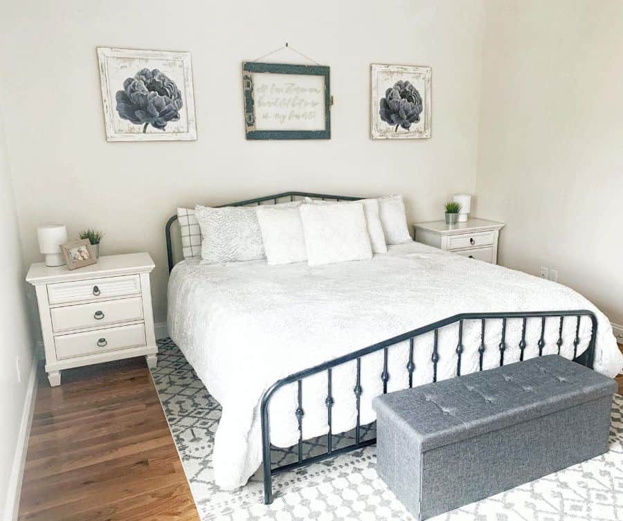 Bright bedroom with a white bedspread, gray ottoman, and matching bedside tables.