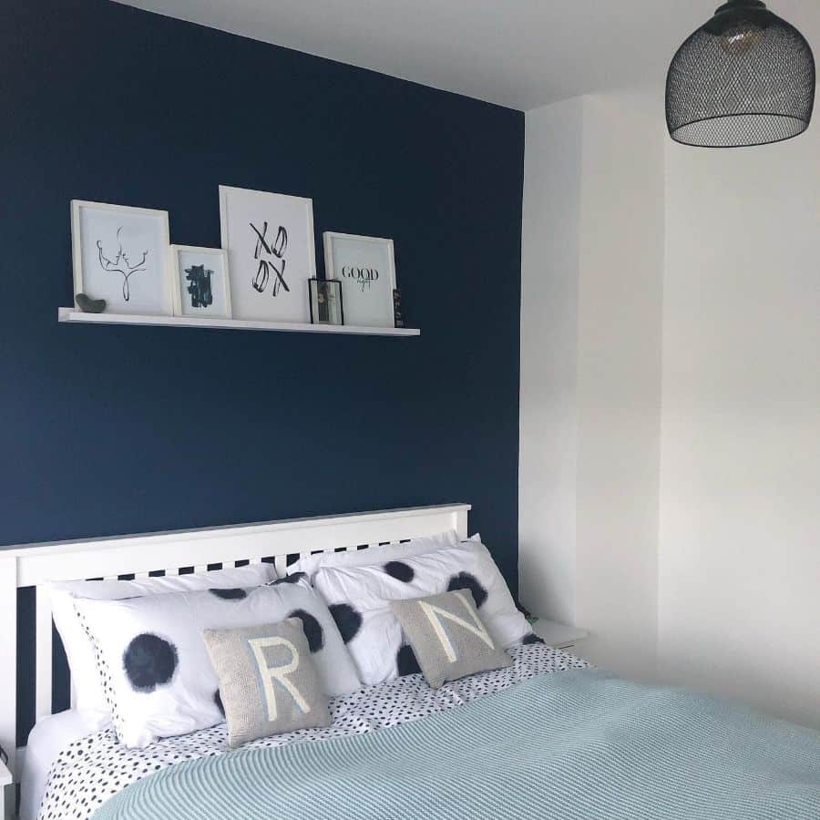 blue bedroom accent wall with framed art on shelf 
