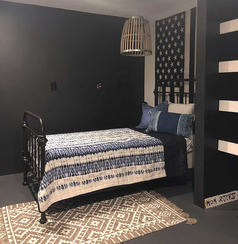 small black bedroom with american flag wall art and black cast iron bed