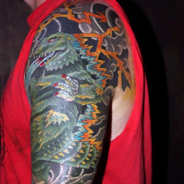 Black And Colorful Tattoo Of Godzilla Fighting Mans Sleeve