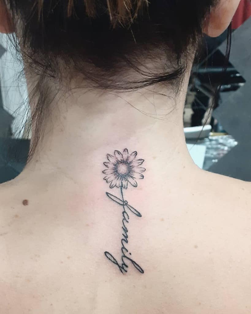 Back of the neck black and grey daisy tattoo with stem forming cursive script ‘family’