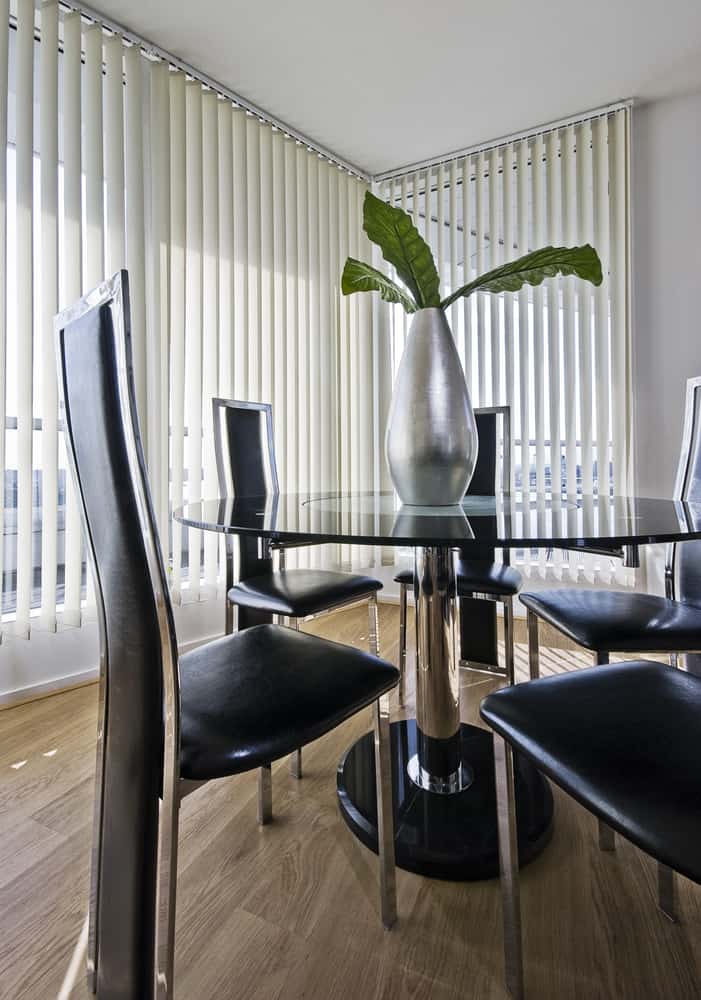 white blinds dining room with glass table and black chairs 