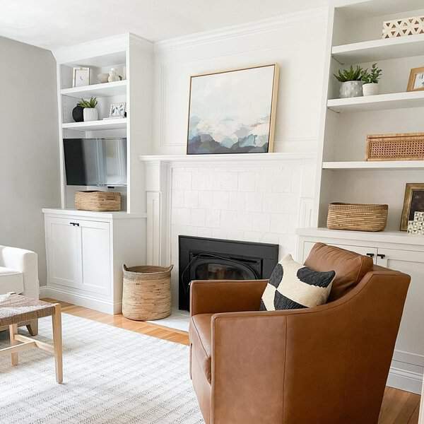 Bright living room with white built-in shelves, a fireplace, and a cozy leather armchair.