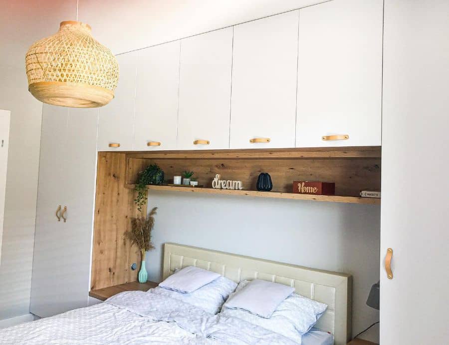 Bedroom with built-in storage above bed, wooden accents, and woven pendant light.