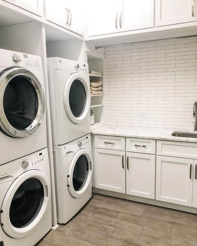 white cabinet laundry room dual vertical stacked washer and dryer