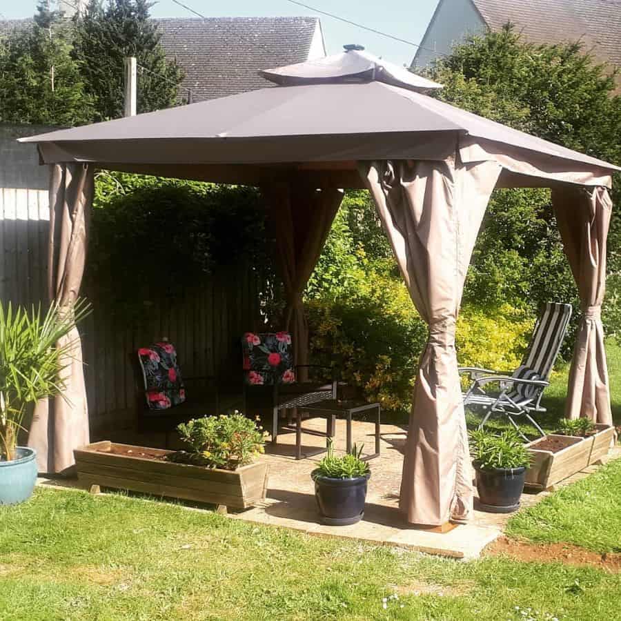 canopy gazebo small garden wicker chairs floral pillows pot plants and planters