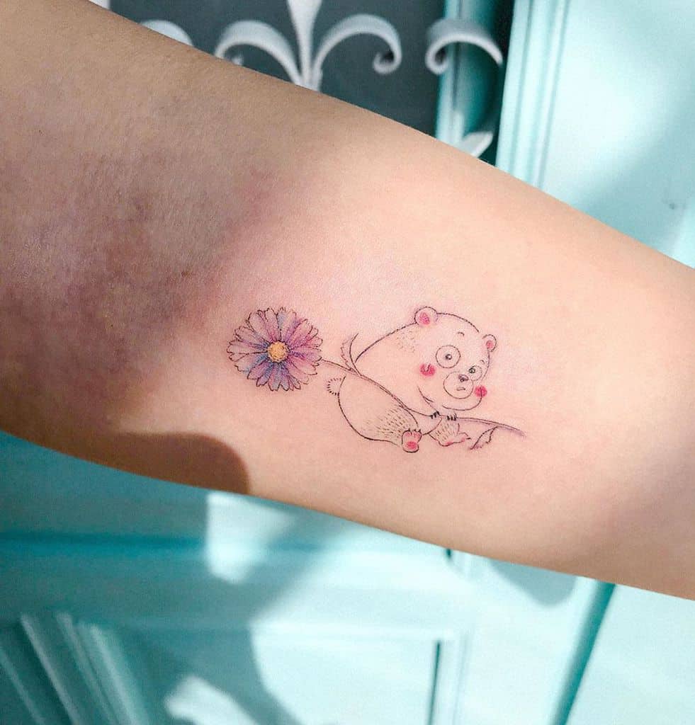 Forearm tattoo small color cartoon bear holding purple daisy