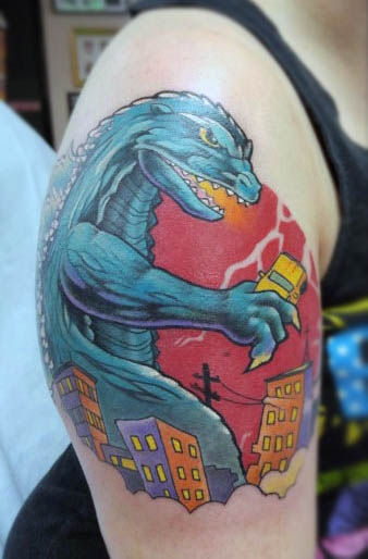 Cartoon Style Tattoo Of Godzilla Eating City On Mans Bicep