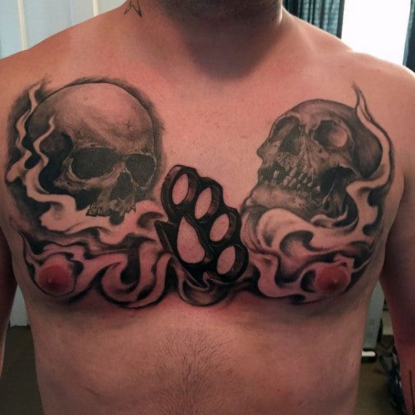 Center Of Chest Male Brass Knuckles Tattoo With Skulls