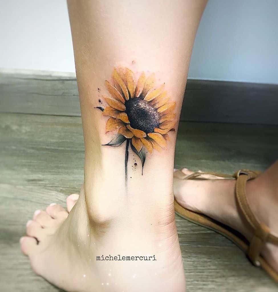 medium-sized color tattoo on woman's ankle of realistic sunflower with leaves