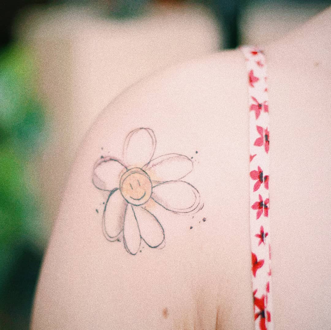 Shoulder tattoo color child-like smiling daisy