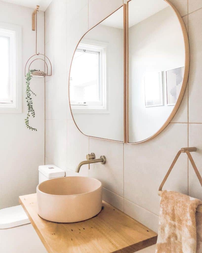 boho style bathroom with round pink sink and abstract wall mirror 