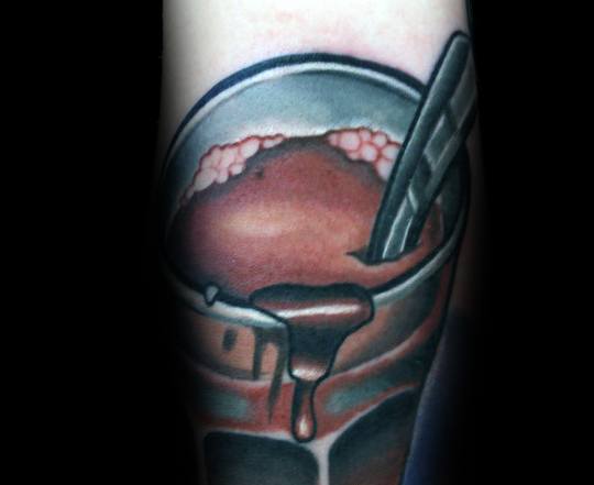 Tattoo of a rich chocolate milkshake in a glass, with ice cream scoops, dripping syrup, and a straw, creating a bold and tasty design.