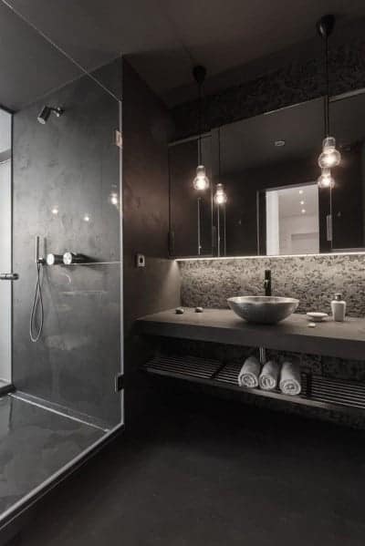 Modern dark bathroom with glass shower, vessel sink, hanging lights, and sleek minimalist design.