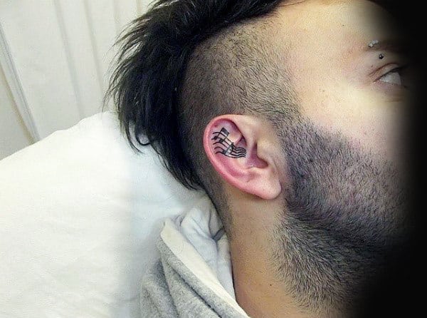 Minimalist music note tattoo behind the right ear