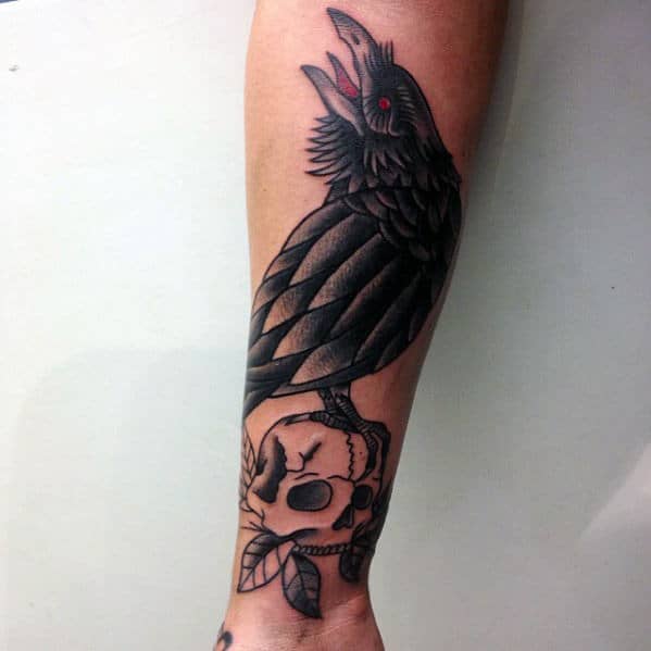 Cool Traditional Crow Standing On Skull Tattoo For Guys On Lower Leg