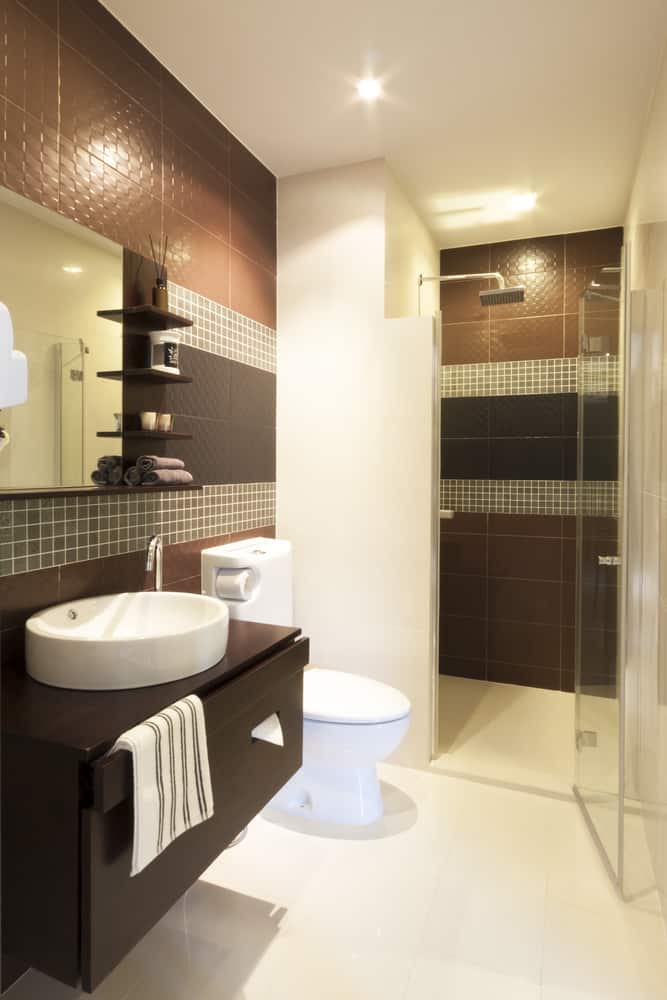 brown wall tile bathroom walk-in shower white sink wall shelves 