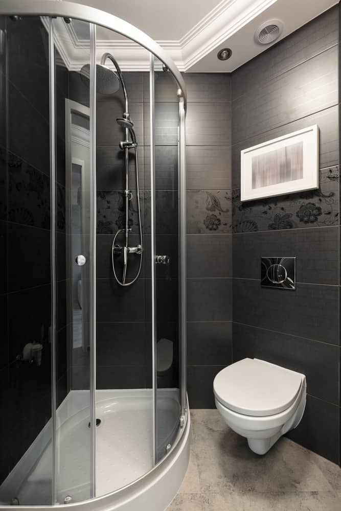 small corner shower in black tile bathroom 