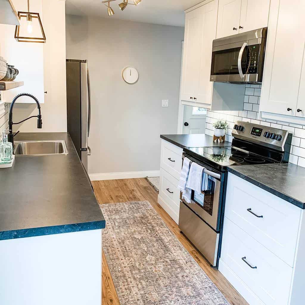 small country style galley kitchen white cabinets black bench top 