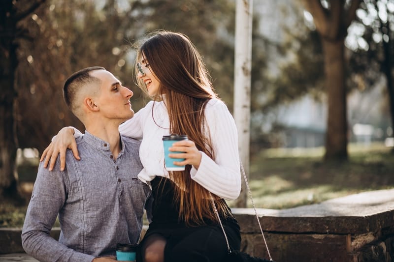 couple dating outdoor while drinking coffee