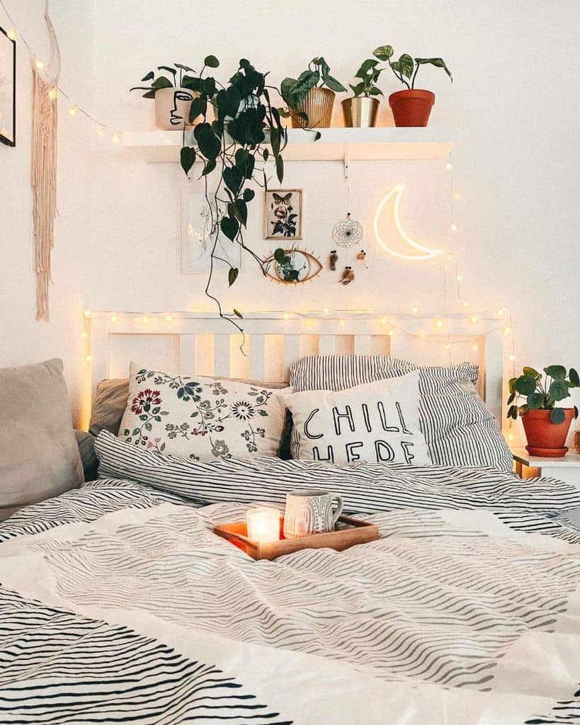 cozy bedroom white bed frame wall shelf fairy lights pot plants 