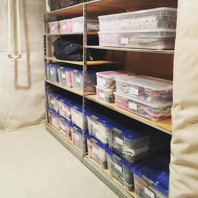 Basement shelves with labeled bins storing craft supplies and clothes for organized storage.