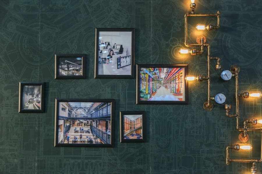 stock images in frames hanging on green accent wall with abstract pipe lighting 