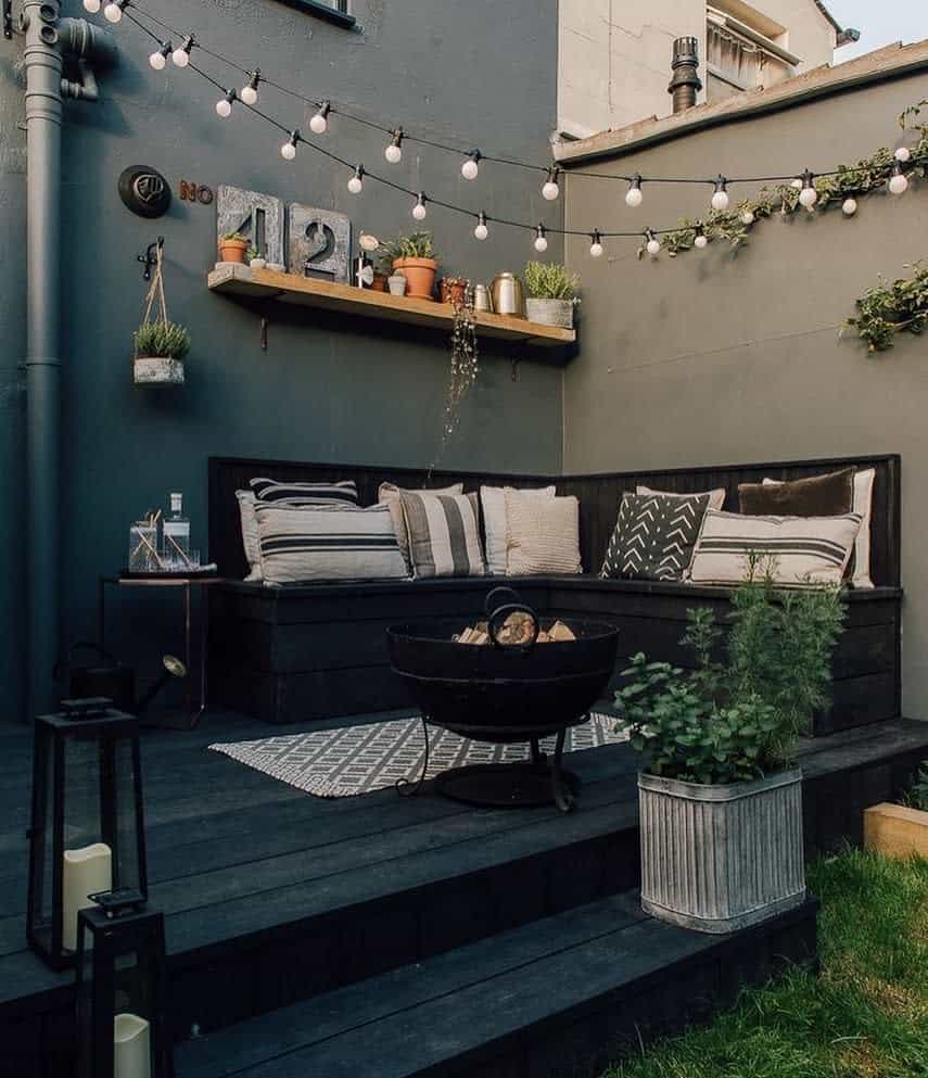 small corner deck patio with bench seating and string lights