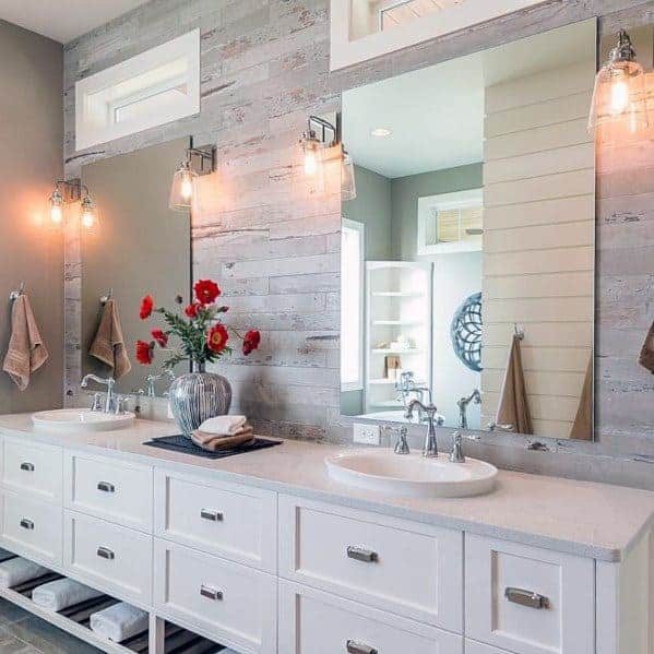 Bright bathroom with double sinks, rustic wood accent wall, and industrial light fixtures.