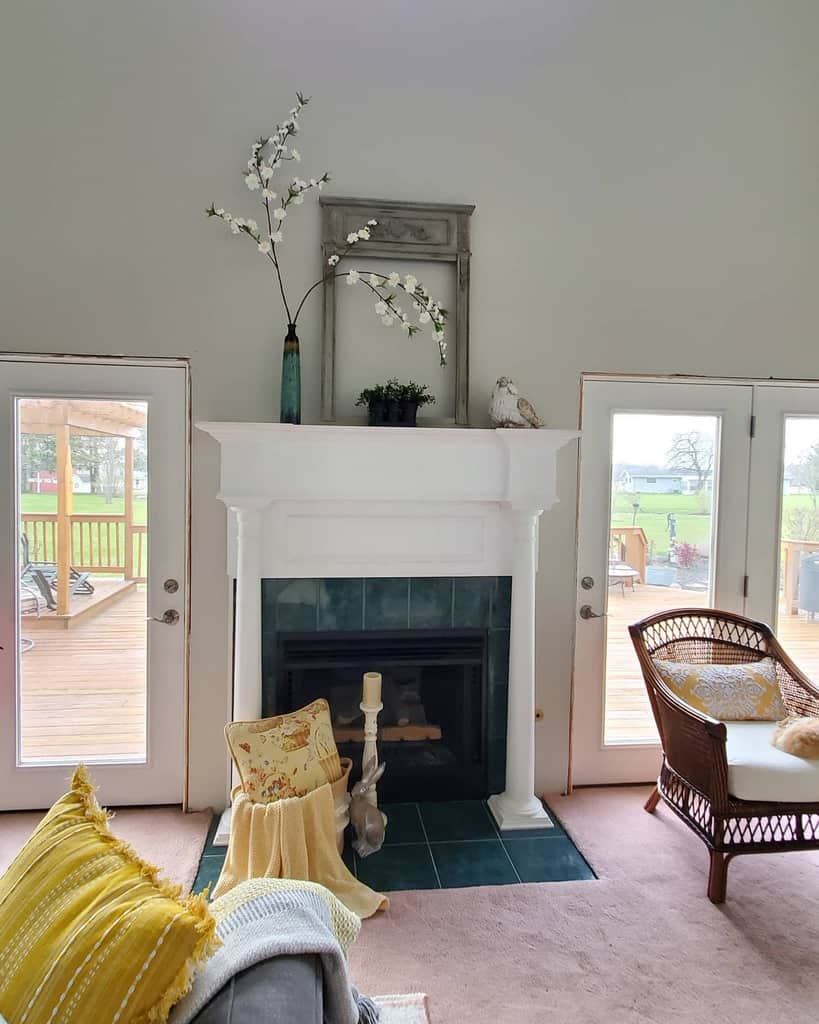 white fireplace with green tiles candlestick vase with flowers bird statue